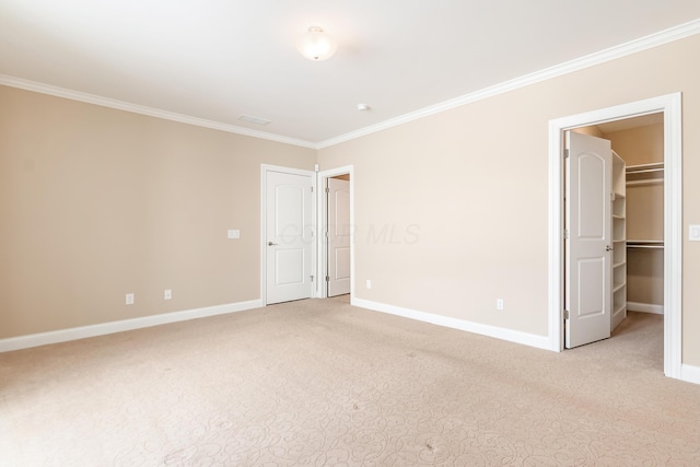 unfurnished bedroom with crown molding, a walk in closet, light carpet, and a closet