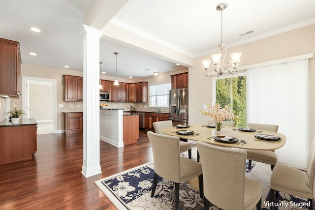 dining space featuring ornate columns, dark hardwood / wood-style floors, sink, ornamental molding, and an inviting chandelier