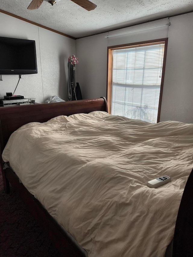 bedroom featuring a textured ceiling, ceiling fan, and crown molding