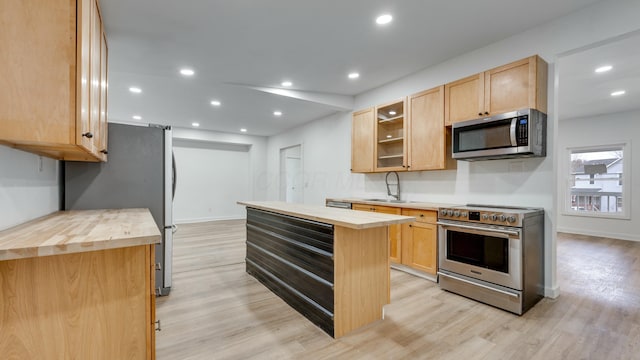 kitchen featuring a kitchen island, appliances with stainless steel finishes, light brown cabinetry, butcher block counters, and sink