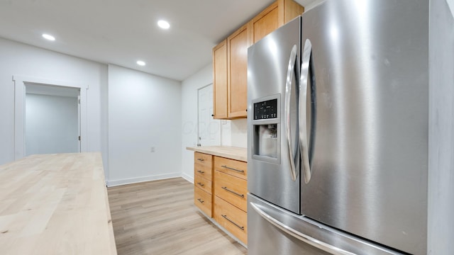 kitchen with light brown cabinets, stainless steel fridge, wood counters, and light hardwood / wood-style flooring