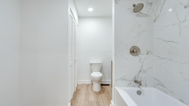 bathroom with tiled shower / bath combo, hardwood / wood-style floors, and toilet