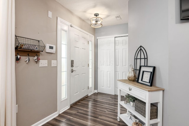 foyer entrance with a textured ceiling, dark hardwood / wood-style floors, and a notable chandelier