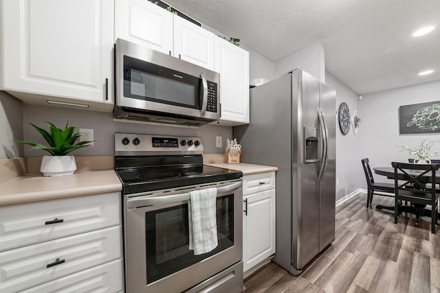 kitchen with white cabinets, wood-type flooring, a textured ceiling, and appliances with stainless steel finishes