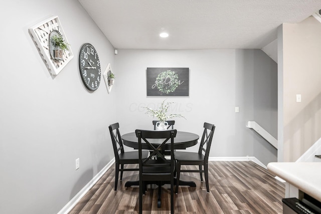 dining space with dark hardwood / wood-style flooring, a textured ceiling, and vaulted ceiling