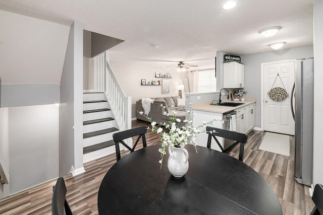 dining space with dark hardwood / wood-style flooring, ceiling fan, sink, and a textured ceiling