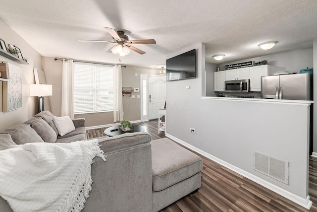 living room featuring a textured ceiling, ceiling fan, and dark hardwood / wood-style floors