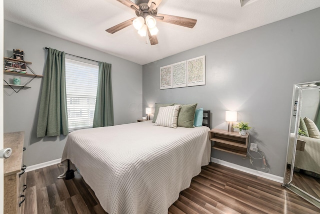 bedroom with ceiling fan, dark wood-type flooring, and a textured ceiling