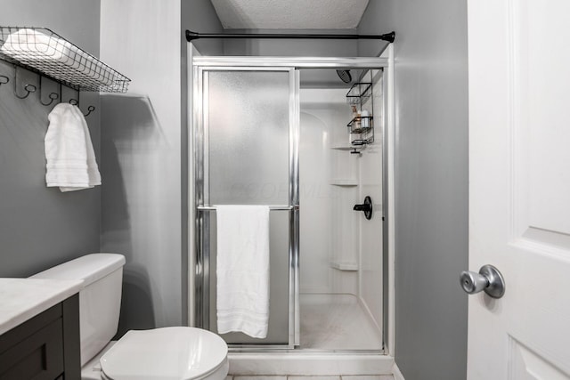 bathroom featuring a shower with door, vanity, a textured ceiling, and toilet