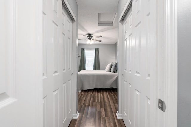 hallway with a textured ceiling and dark wood-type flooring