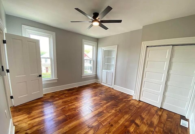 unfurnished bedroom with a closet, dark wood-type flooring, and ceiling fan