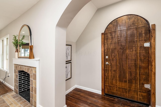 entrance foyer with a fireplace, hardwood / wood-style floors, and lofted ceiling