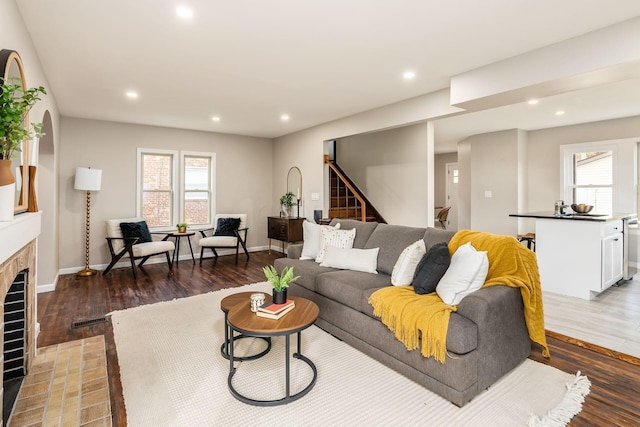 living room with a tile fireplace, wood-type flooring, and a wealth of natural light