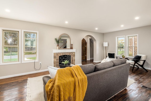 living room with a fireplace and dark wood-type flooring