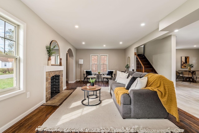 living room featuring a tile fireplace, dark hardwood / wood-style flooring, and a healthy amount of sunlight