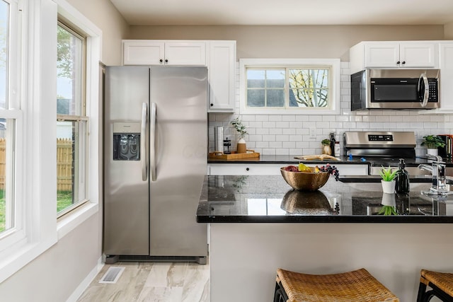 kitchen featuring backsplash, white cabinetry, and stainless steel appliances