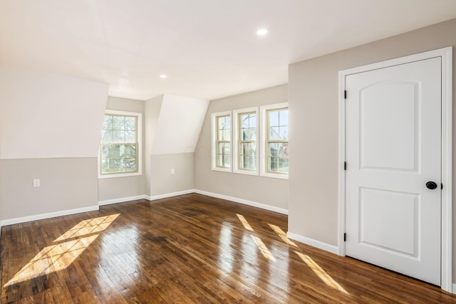 additional living space featuring dark wood-type flooring, a wealth of natural light, and vaulted ceiling