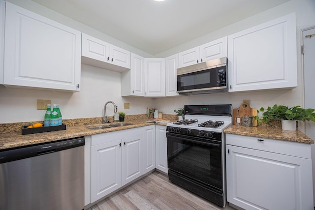 kitchen featuring white cabinetry, sink, light hardwood / wood-style flooring, stone countertops, and appliances with stainless steel finishes