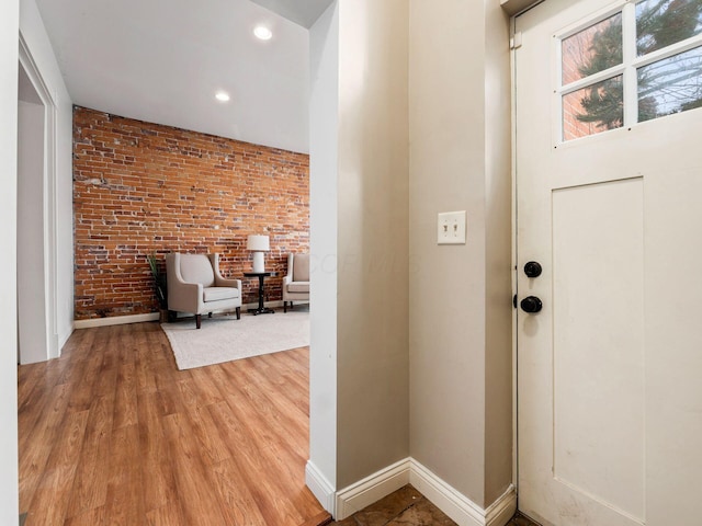 entryway featuring hardwood / wood-style flooring and brick wall