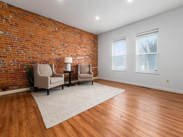 unfurnished room featuring brick wall and light wood-type flooring