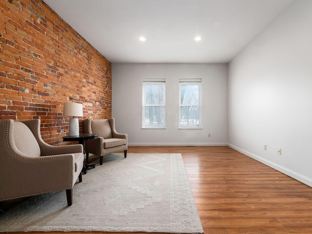 unfurnished room with brick wall and hardwood / wood-style floors