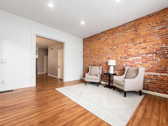 unfurnished room featuring hardwood / wood-style flooring and brick wall