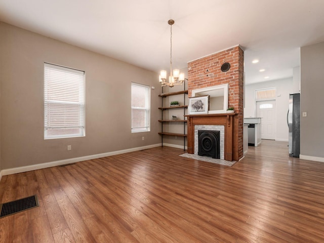 unfurnished living room with a notable chandelier, hardwood / wood-style flooring, and a fireplace