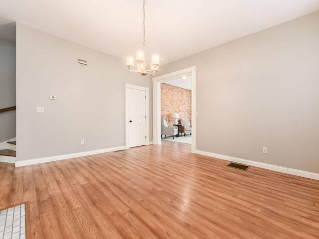 empty room featuring light wood-type flooring and a notable chandelier