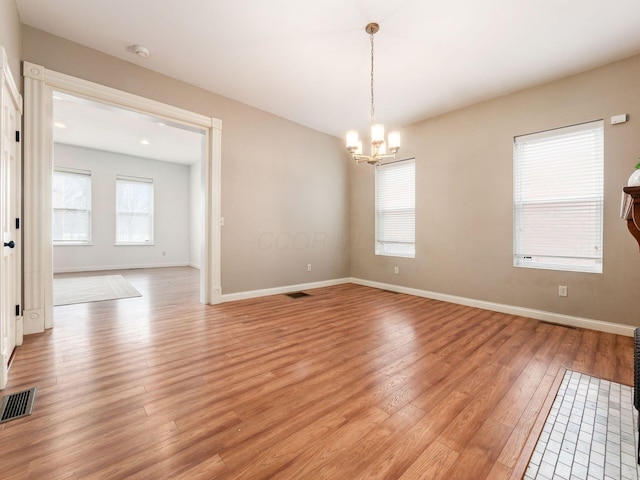 unfurnished room with light hardwood / wood-style floors and an inviting chandelier