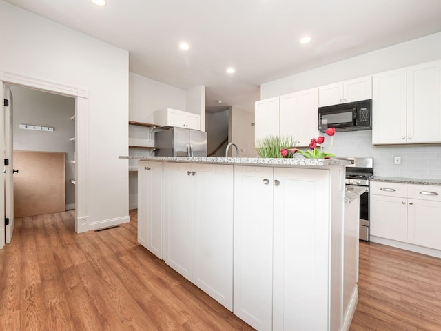 kitchen featuring white cabinetry, appliances with stainless steel finishes, and an island with sink