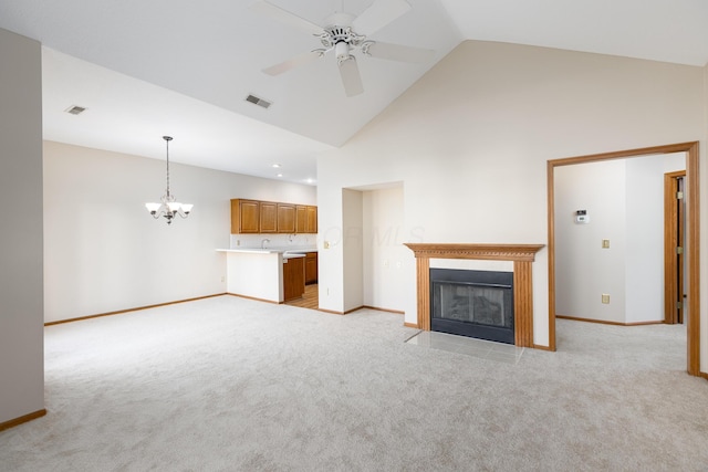 unfurnished living room featuring high vaulted ceiling, light colored carpet, and ceiling fan with notable chandelier