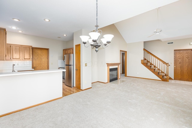 kitchen featuring light carpet, stainless steel fridge, backsplash, ceiling fan with notable chandelier, and lofted ceiling