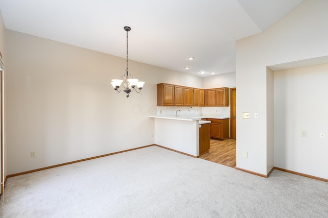 kitchen featuring kitchen peninsula, decorative light fixtures, a chandelier, and light colored carpet