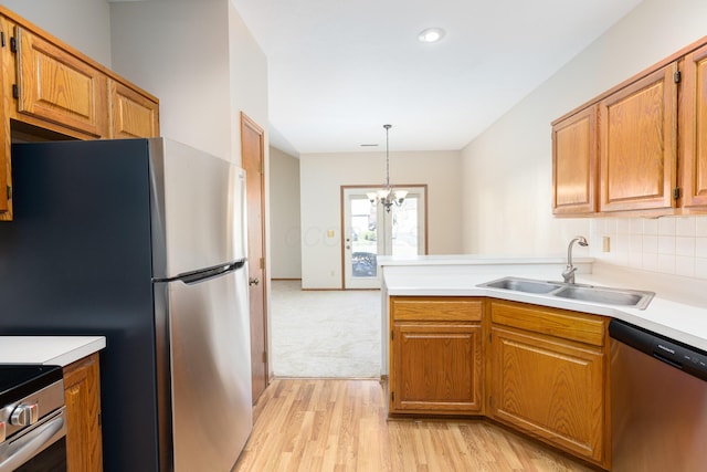 kitchen with light wood-type flooring, stainless steel appliances, sink, an inviting chandelier, and hanging light fixtures