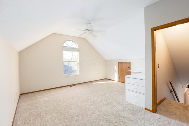 additional living space with ceiling fan, light colored carpet, and vaulted ceiling