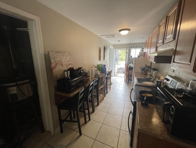 kitchen featuring light tile patterned floors, sink, and stainless steel electric range oven