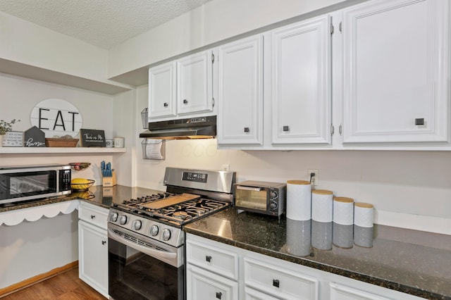 kitchen with white cabinets, dark stone countertops, light wood-type flooring, a textured ceiling, and appliances with stainless steel finishes