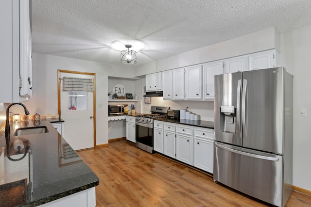 kitchen with white cabinets, sink, light hardwood / wood-style flooring, dark stone countertops, and stainless steel appliances