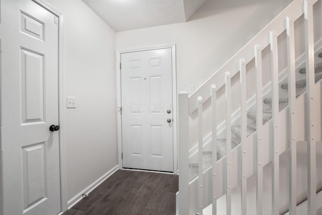 doorway featuring a textured ceiling and dark wood-type flooring