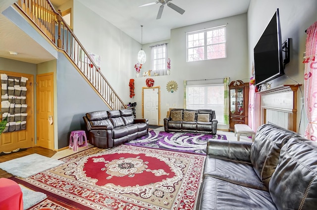 living room featuring ceiling fan, wood-type flooring, a wealth of natural light, and a towering ceiling