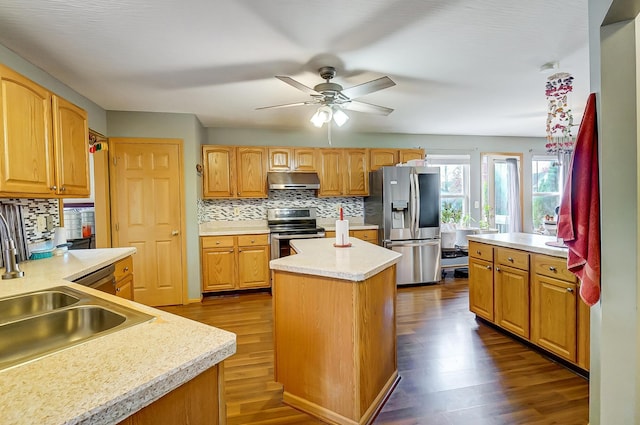 kitchen featuring appliances with stainless steel finishes, dark hardwood / wood-style floors, a kitchen island, and sink