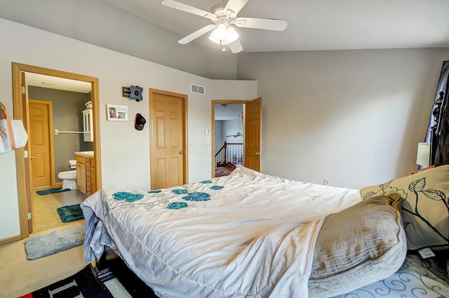 carpeted bedroom with ensuite bath, ceiling fan, and vaulted ceiling