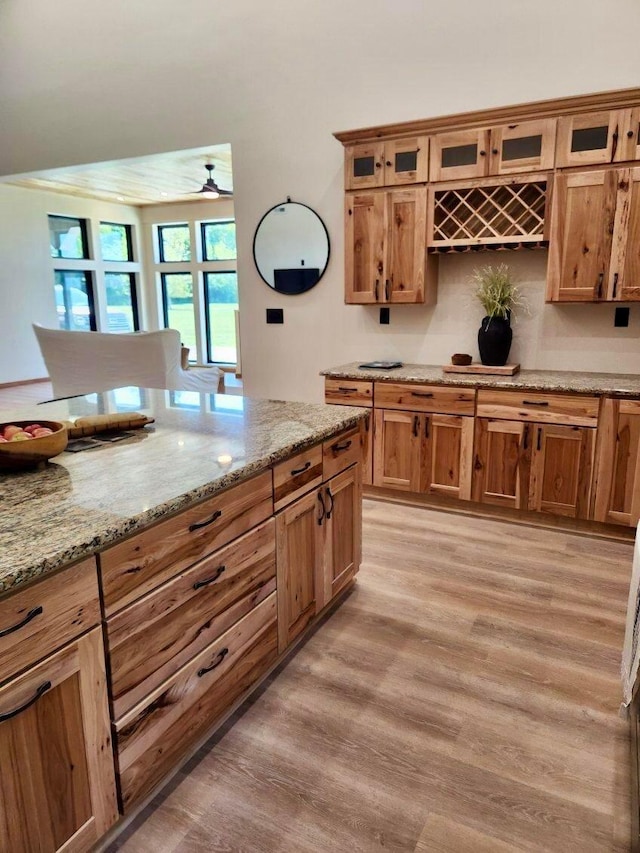 kitchen with ceiling fan, light stone countertops, and light hardwood / wood-style flooring