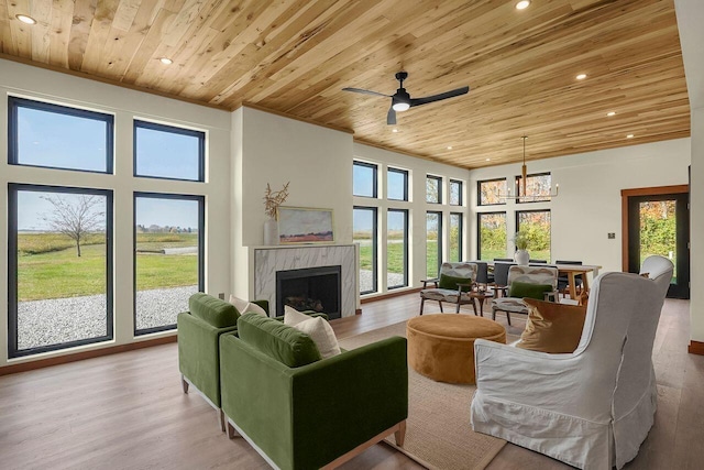 living room featuring ceiling fan with notable chandelier, light hardwood / wood-style floors, wood ceiling, and a fireplace