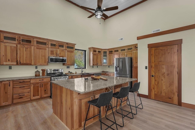 kitchen featuring a kitchen bar, appliances with stainless steel finishes, light stone counters, sink, and a kitchen island