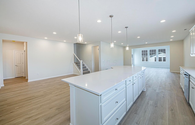 kitchen with decorative light fixtures, white cabinets, a center island, stainless steel dishwasher, and light hardwood / wood-style floors