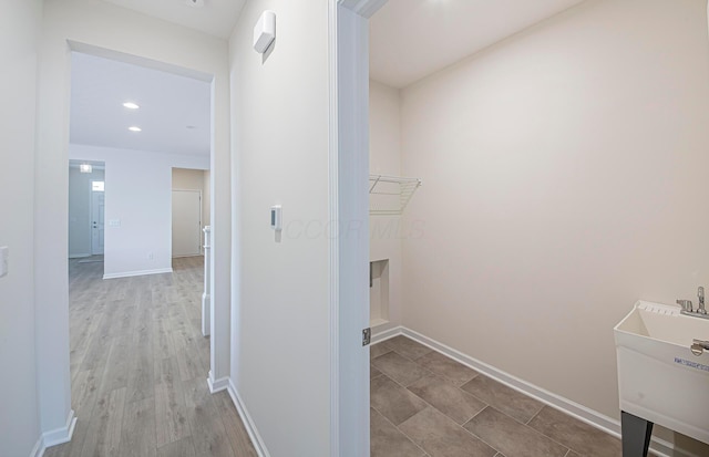 laundry room featuring sink and light hardwood / wood-style flooring