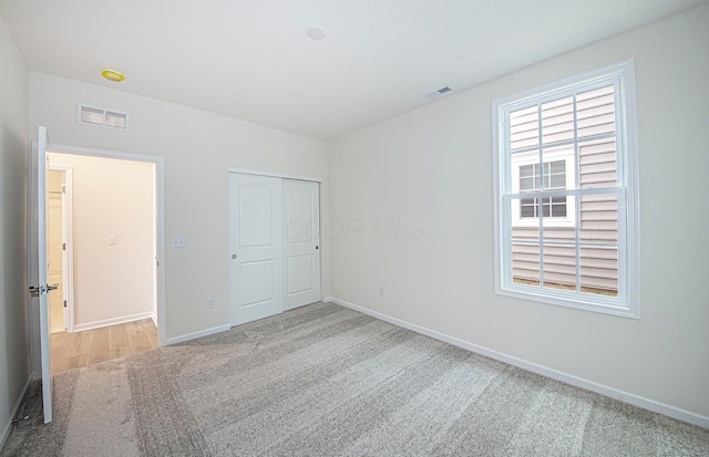 unfurnished bedroom with a closet and light carpet