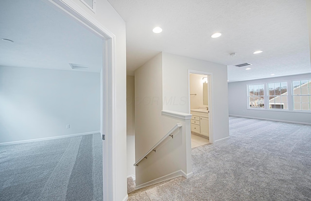 hallway with light carpet and a textured ceiling