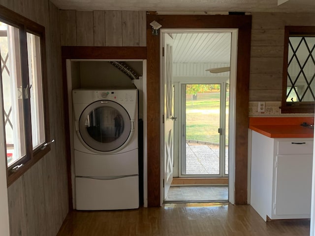 washroom featuring wooden walls, wood-type flooring, and washer / dryer